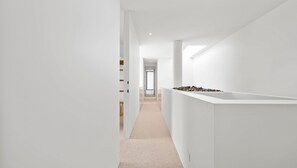En modern, minimalistisk hall med vita väggar och ett mattbeklätt golv.
