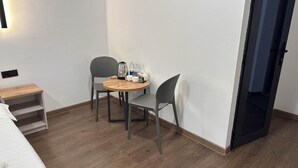 A small room with a bed, a wooden nightstand, a round table with chairs, and a door leading to another room. - Gatsby Djal (Bishkek)