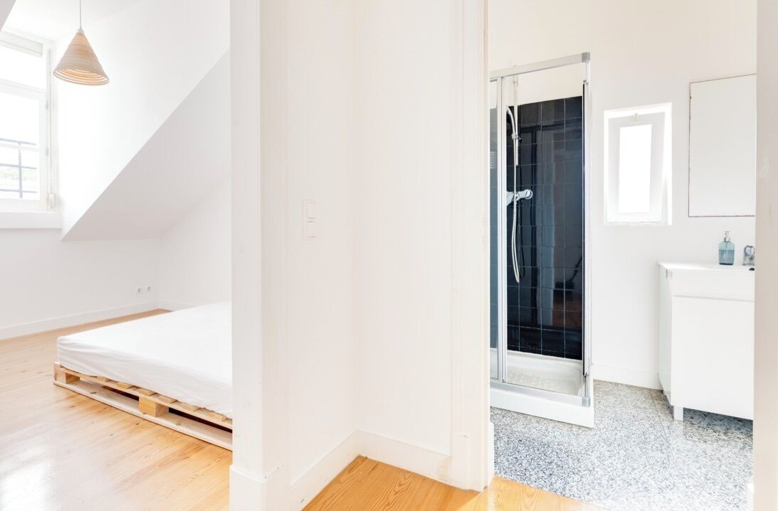 Een slaapkamer met een bed, een douche en een witte dressoir.