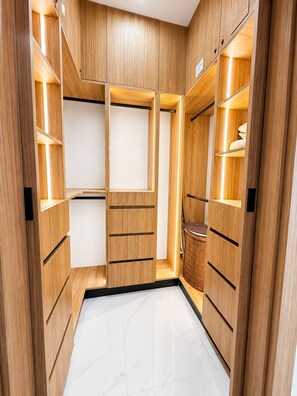 Vestidor con estantes y cajones de madera, y suelo de mármol.
