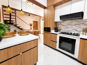 Eine moderne Küche mit Holzausstattung, einem eingebauten Backofen und einer Mikrowelle.