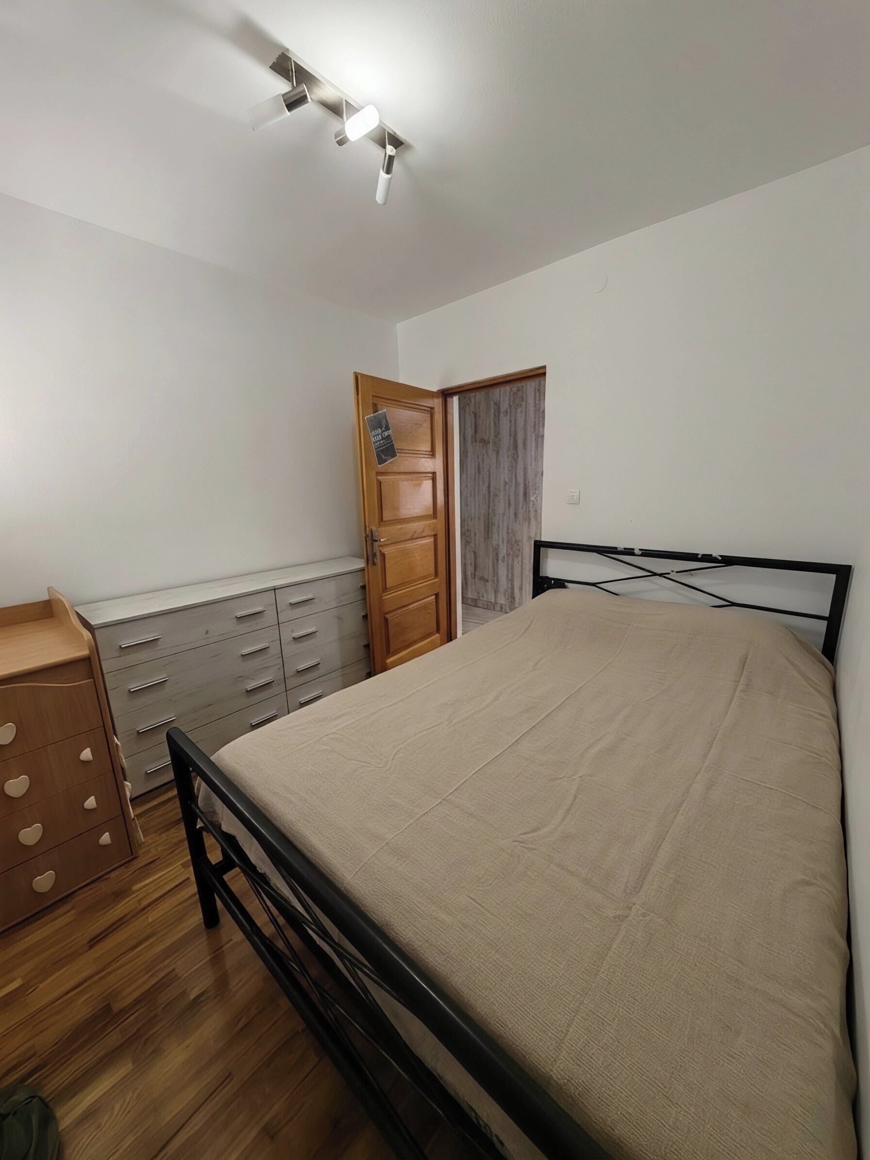 A bedroom with a bed, wooden dresser, and a wardrobe.