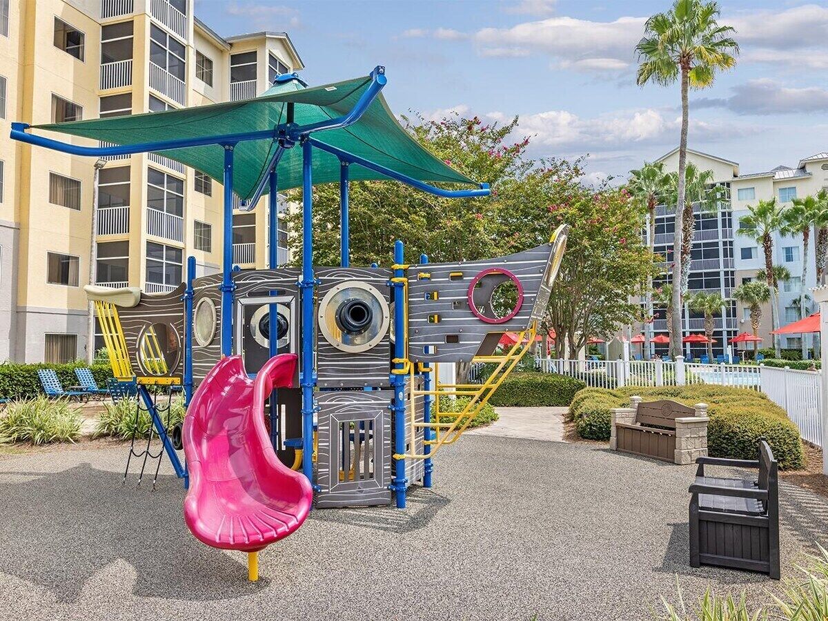 A playground with a slide, climbing structures, and a shaded area.