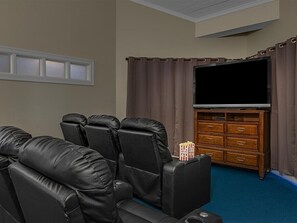 A home theater room with leather reclining chairs, a flat-screen TV, a wooden entertainment center, and a blue carpet. - Family-Friendly 2 Bedroom Villa Panama City Resort (Panama City)
