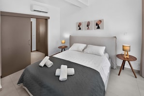 A modern bedroom with a bed, two bedside tables, a wardrobe, and artwork on the wall. - Eclipse: New Private 4-Bed Villa, Central Napa (Ayia Napa)