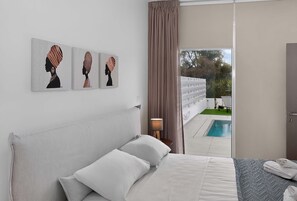 A bedroom with a bed, a nightstand, a lamp, and a view of a swimming pool. - Eclipse: New Private 4-Bed Villa, Central Napa (Ayia Napa)