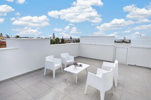 A rooftop terrace with white chairs and a table, a clear blue sky, and a view of the cityscape. - Celeste: Private 4BDR Villa, Central Napa (Ayia Napa)