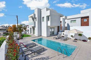 A modern residential building with a swimming pool, outdoor seating, and a well-maintained garden. - Celeste: Private 4BDR Villa, Central Napa (Ayia Napa)