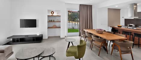 Una sala de estar moderna con un televisor de pantalla plana, un sofá, una mesa de centro y un comedor con una mesa de madera y sillas.