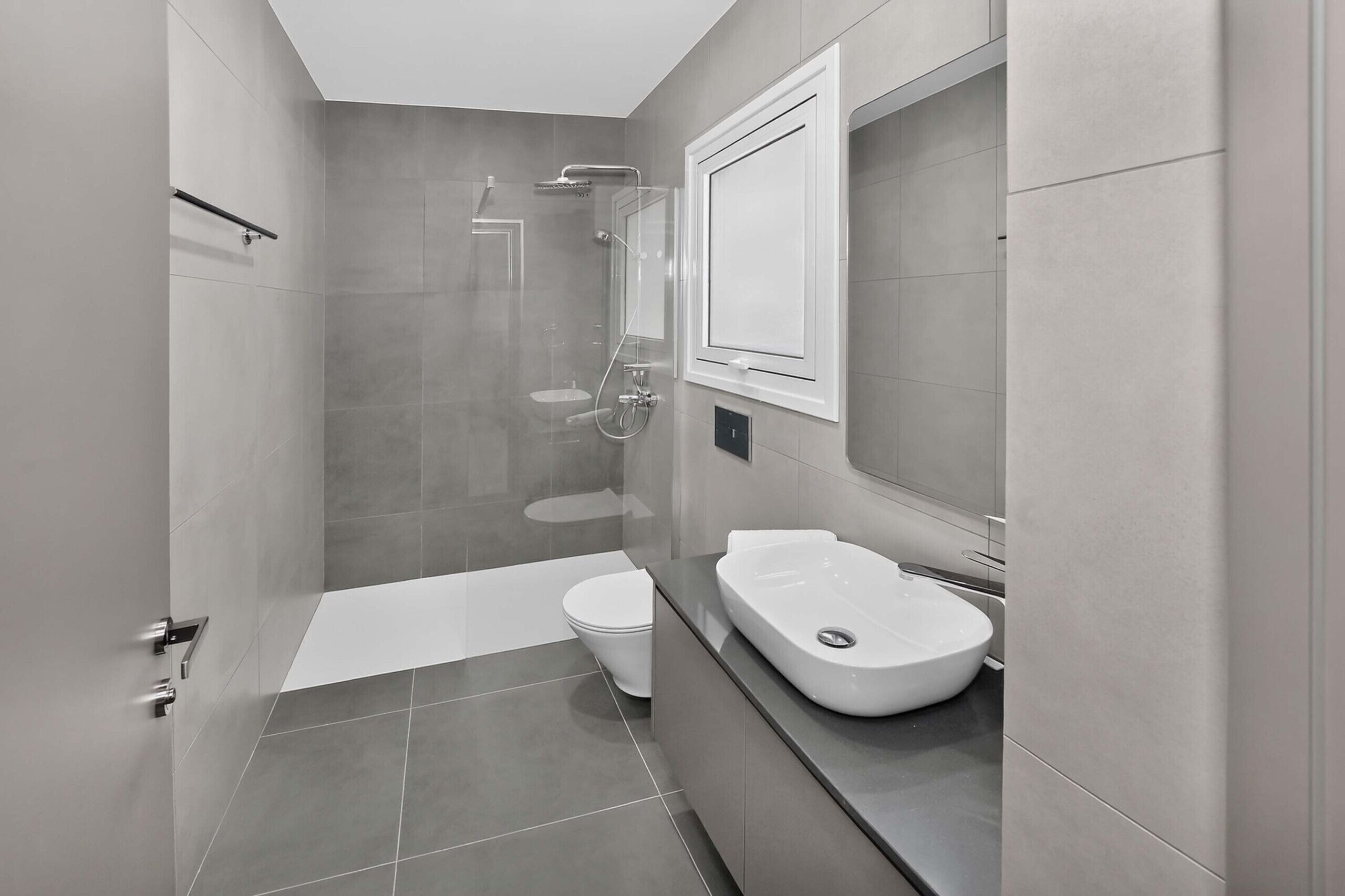 A modern bathroom with a glass-enclosed shower, a white toilet, and a vanity with a sink.