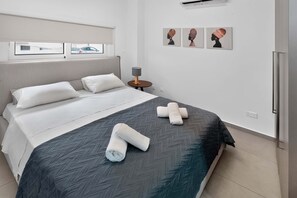 A hotel room with a bed, pillows, a nightstand, a lamp, and three wall art pieces. - Celeste: Private 4BDR Villa, Central Napa (Ayia Napa)