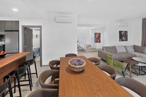 A modern living room with a wooden dining table, grey sofa, and a staircase leading to an upper level. - Celeste: Private 4BDR Villa, Central Napa (Ayia Napa)