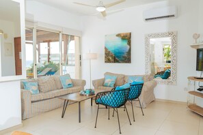 A living room with striped sofas, a coffee table, and blue chairs. - Artisan Seafront Villa - Escape (Protaras)
