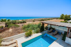 A pool area with a view of the sea, a covered seating area, and a sign indicating pool rules. - Artisan Seafront Villa - Escape (Protaras)