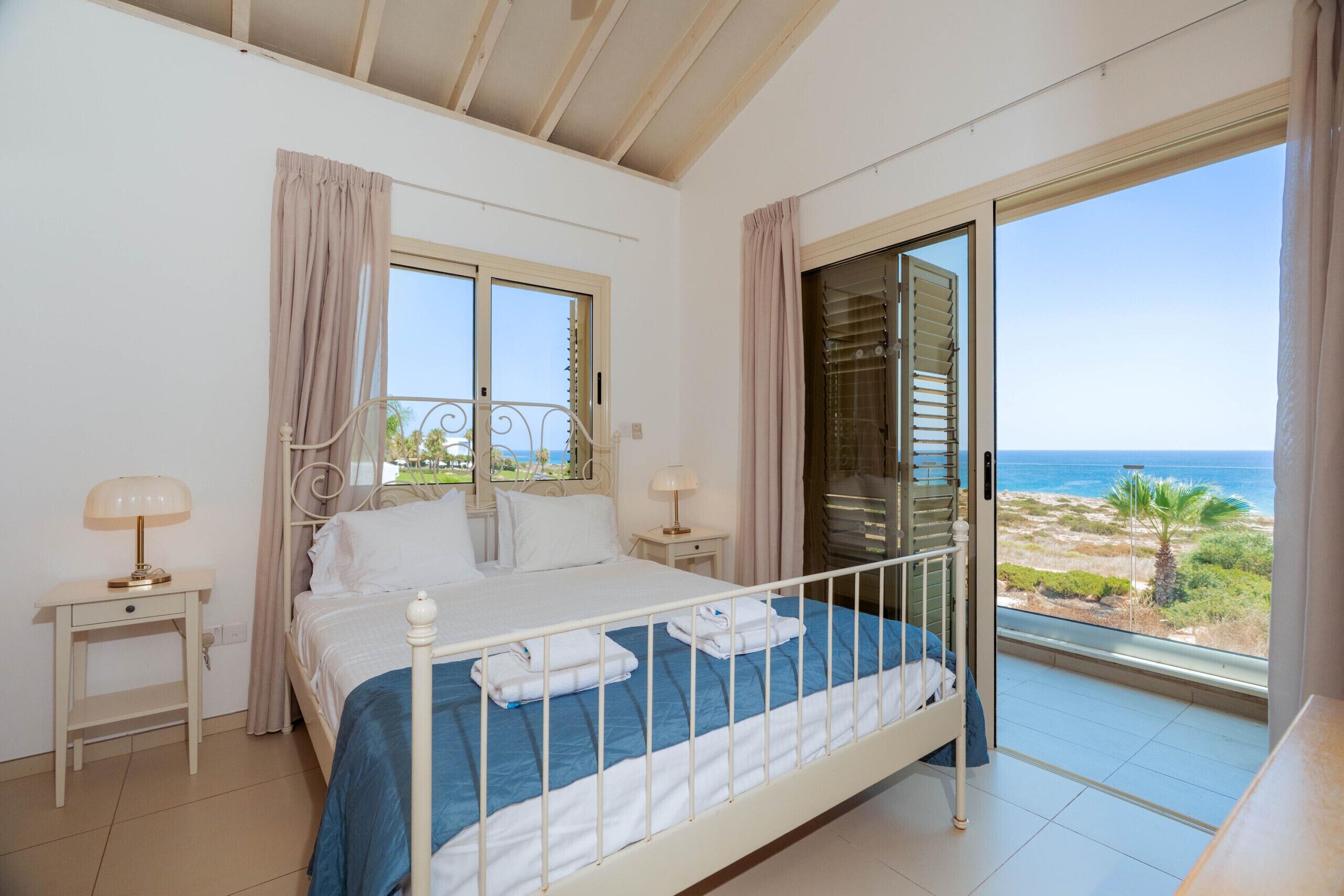 Ein Schlafzimmer mit einem Bett, zwei Nachttischen, einem Fenster und Meerblick.