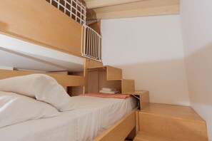 A bunk bed with a wooden headboard, a small wooden desk, and a white wall. - Artisan Seafront Villa - Treehouse (Protaras)