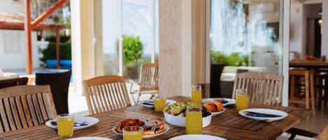 Une table de salle à manger en bois, avec des assiettes, des couverts et des boissons, entourée de chaises.