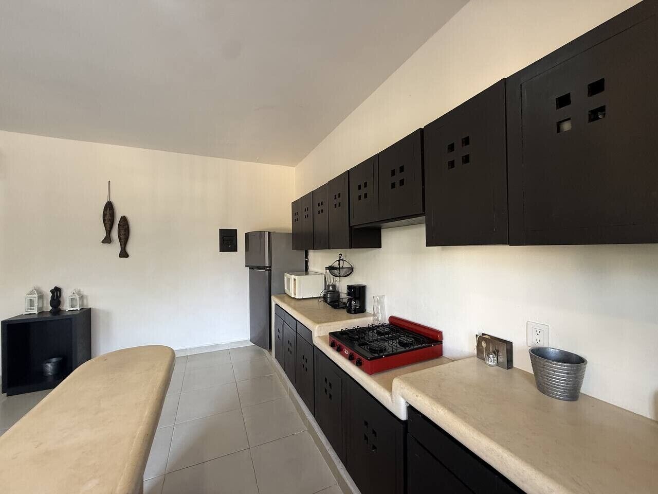 A compact kitchen with dark cabinets, a red stove, and a small countertop area.