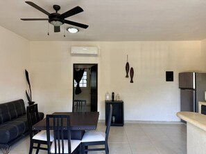 Ein modernes Wohnzimmer mit Essbereich, Deckenventilator, Klimaanlage und Küchenzeile mit Kühlschrank.