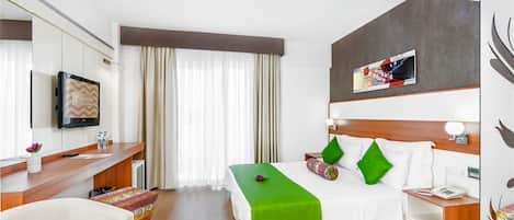 A hotel room with a bed, bedside table, lamp, and a television on the wall.