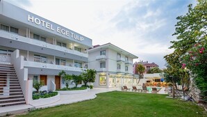 Ett hotell med ett skylt med hotellets namn, flera våningar, ett poolområde och en välskött gräsmatta.