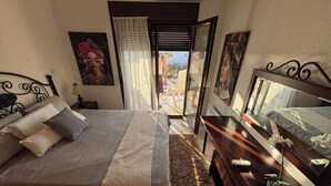 A bedroom with a bed, a nightstand, a dresser, and a window with a view. - Halkidikigr (Nikiti)
