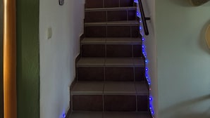 A staircase with blue LED lights, a wall-mounted artwork, and a woven basket. - Halkidikigr (Nikiti)
