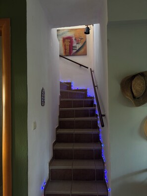 Uma escadaria com luzes LED azuis, uma obra de arte na parede e uma cesta trançada.