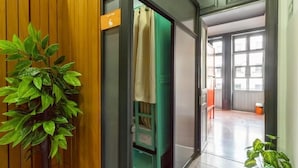 A hallway with a potted plant, a green cabinet, and a sliding glass door leading to a room. - Hostel Bemaro Mexico City (Mexico City)