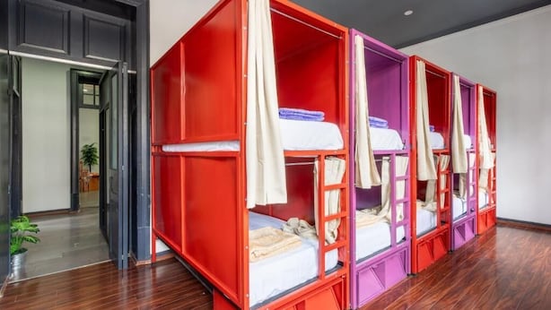 A room with bunk beds, a wooden floor, and a doorway leading to another room. - Hostel Bemaro Mexico City (Mexico City)