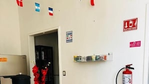A dining area with a table covered in a colorful tablecloth, a fire extinguisher, and a fire alarm on the wall. - Hostel Bemaro Mexico City (Mexico City)