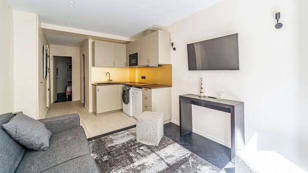 Un apartamento moderno con cocina, sala de estar y una pequeña mesa de comedor.