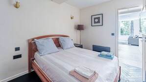 Un dormitorio con cama, mesitas de noche, lámpara y vistas a un balcón exterior.