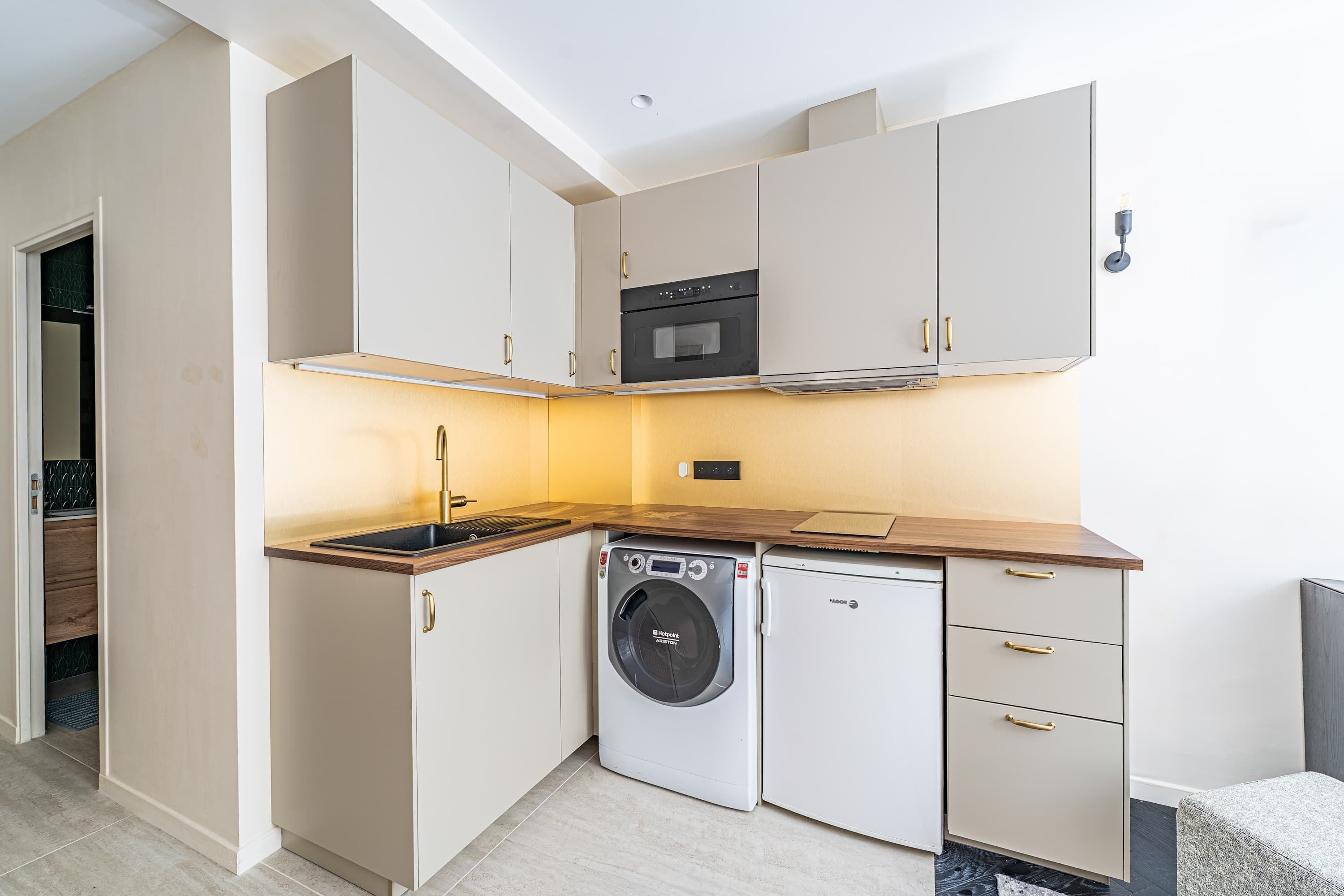 Une cuisine compacte équipée d’un lave-linge, d’un four et d’un petit réfrigérateur.