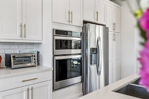 A kitchen with white cabinets, a stainless steel refrigerator, a built-in oven, and a toaster.