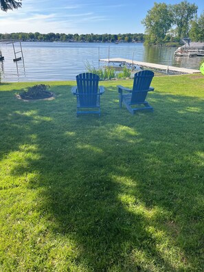 A grassy area with two Adirondack chairs facing a lake. - Cozy Cottage Retreat on Jordan Lake with Amazing Views and Great Fishing (Lake Odessa)