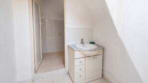 Een badkamer met een wit wastafel, een spiegel en een douchehoek.
