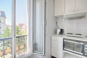 Et køkken med et vindue, hvide skabe, en Bosch emfang og en integreret ovn.