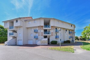 A multi-story residential building with balconies, a central entrance, and a parking area. - Le Scalby - Piscine - Golf (Pornic)
