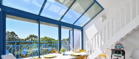 A modern dining area with a large table, yellow chairs, and a view through expansive windows.