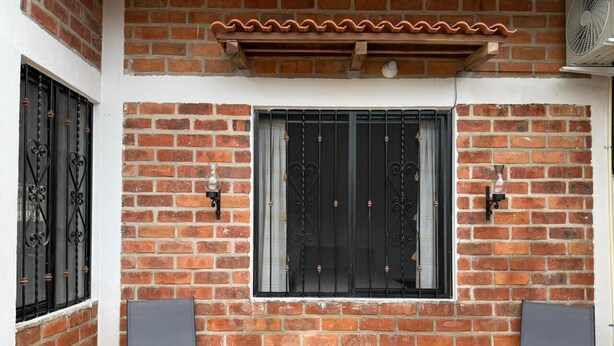 A brick building with two windows, each with decorative iron bars, and two chairs in front. - House near beautiful beaches. Separate entrance, with parking. Secure. (Las Varas)