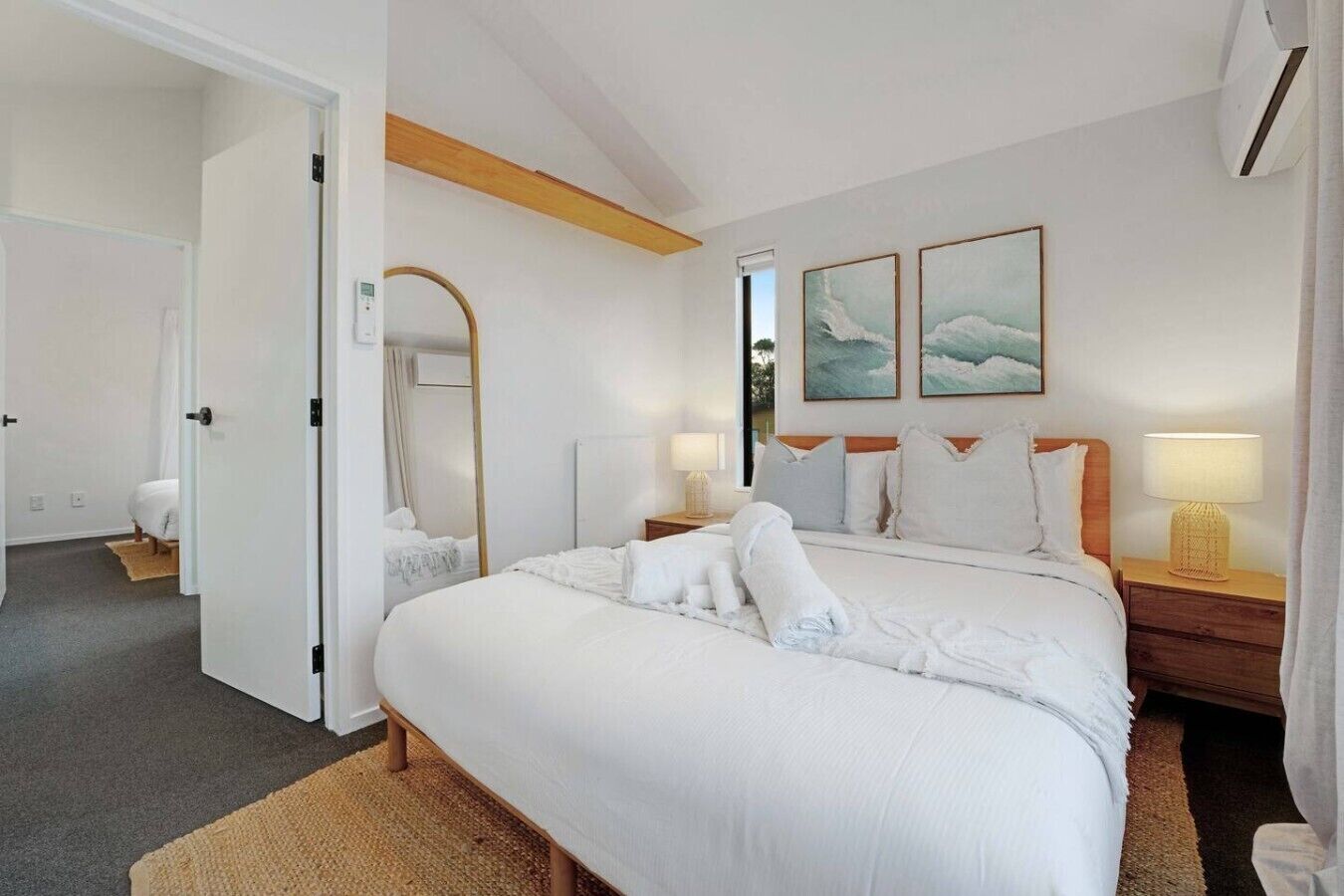 Habitación de hotel con una cama grande, dos mesitas de noche, un espejo y dos cuadros colgados en la pared.