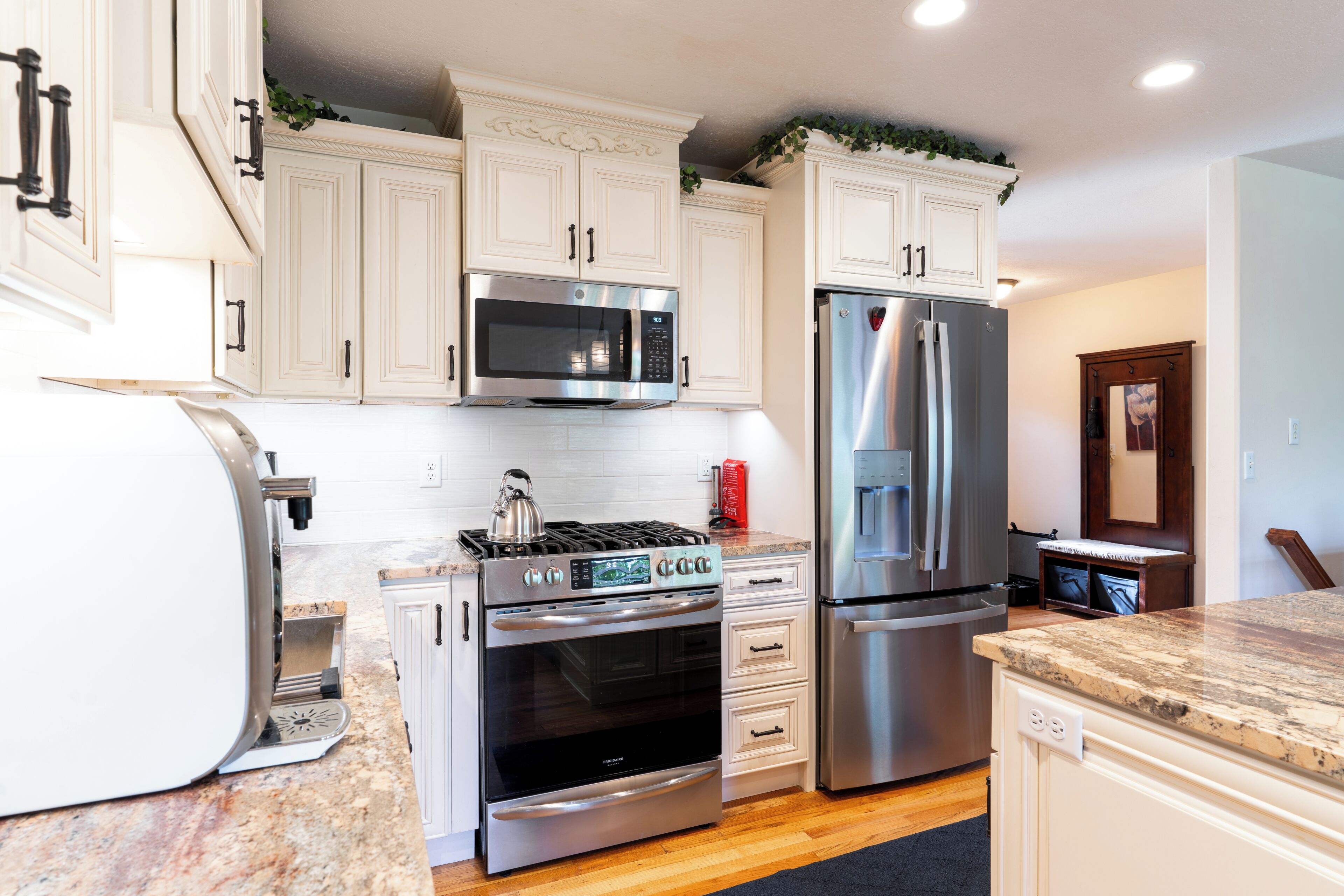 A modern kitchen with white cabinetry, stainless steel appliances, and a granite countertop.