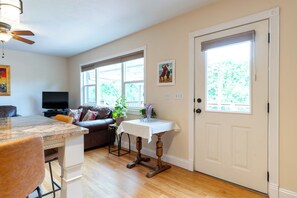 A modern kitchen with a dining area, a television, and a door with a window. - Gibbons Park Cliffside retreat 2 bedroom 2 bath sleeps 8 (Logan)
