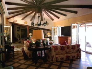 Uma sala de estar com chão quadriculado, um candelabro, um sofá e uma televisão.