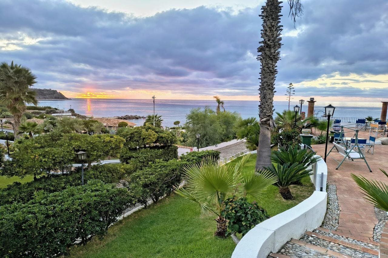 Un jardín ajardinado con vistas al mar al atardecer.