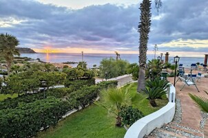 A landscaped garden with a view of the sea at sunset.