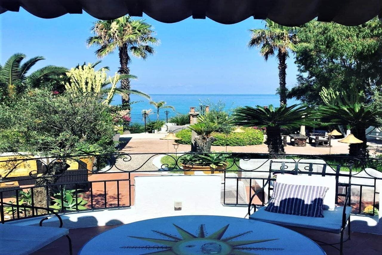 A patio with a sun dial, outdoor seating, and a view of the sea.