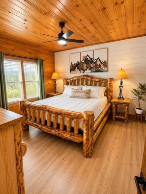 A wooden-themed bedroom with a bed, two bedside tables, a ceiling fan, and a window with curtains. - The Overlook-Luxury Cabin Mtn View Walk to Parkway (Pigeon Forge)