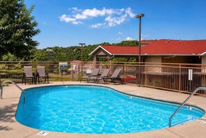 A swimming pool with lounge chairs and a fenced area, surrounded by a building with a red roof. - The Overlook-Luxury Cabin Mtn View Walk to Parkway (Pigeon Forge)